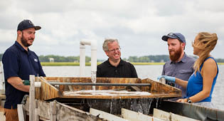 (L to R): John Carroll, Ph.D., Anthony Siccardi, Ph.D., and grad students Christopher Lee and Emily Wells work with the algal turf scrubber at the Priest Landing site.