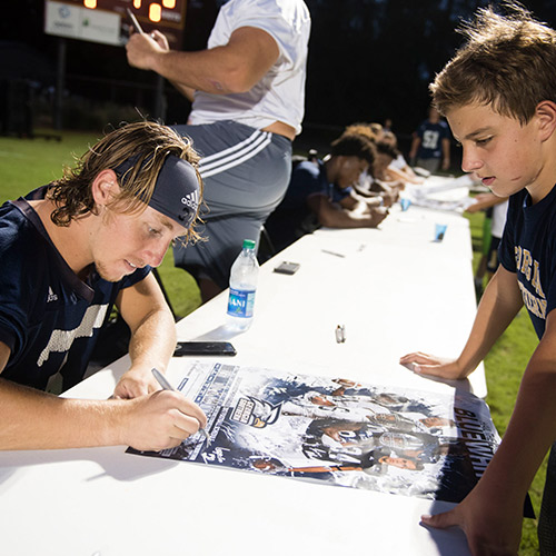 a football player signing a poster for a young boy
