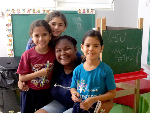 TRIO student in a classroom surrounded by three children