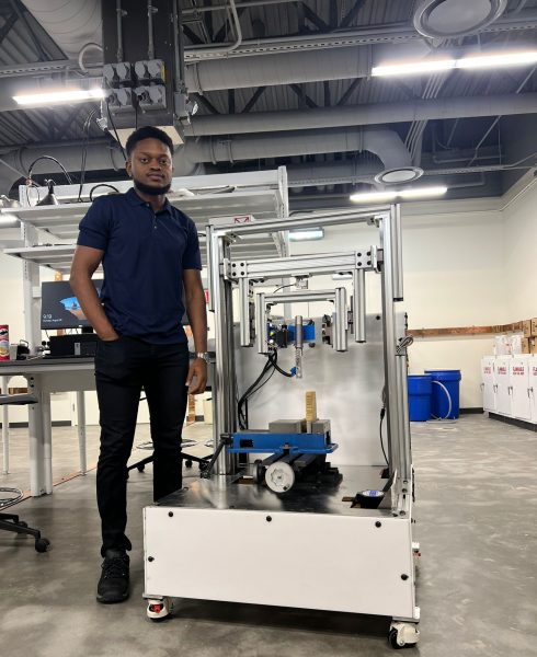 Kenneth Nwagu stands beside the testing device he created