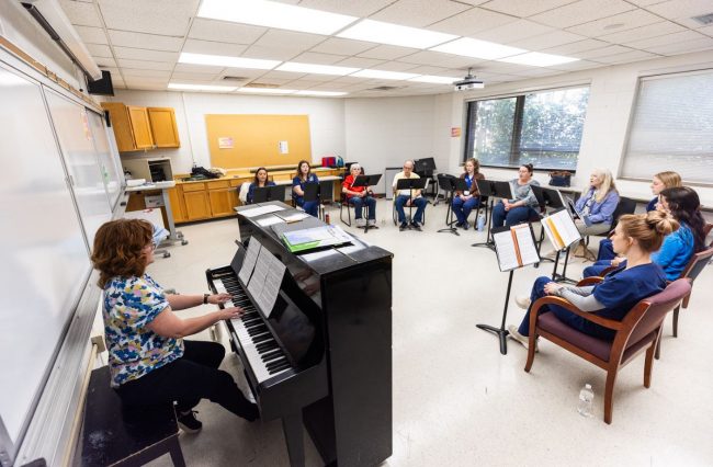 Associate Professor of Voice Emily Grundstad-Hall, DMA, left, plays the piano while members of the Savannah Song Birds sing. 